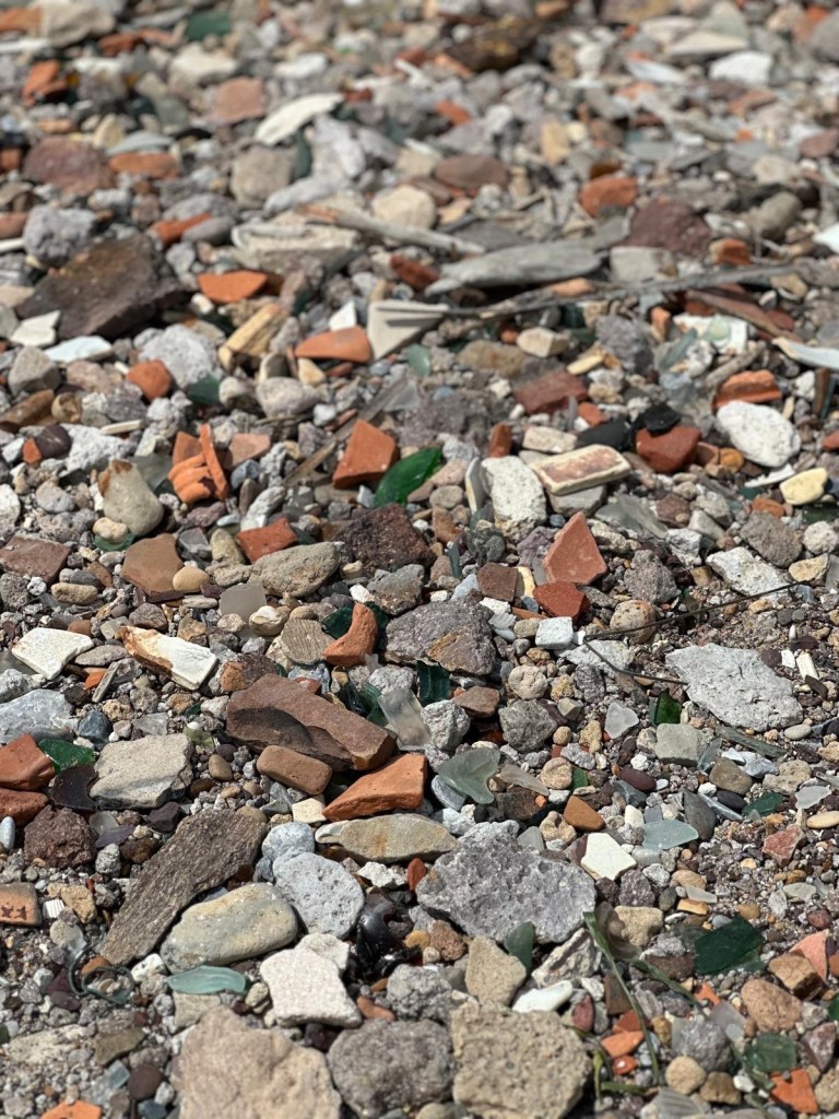 Sea glass and broken pottery in the rocks on a beach in Sardinia, Italy 