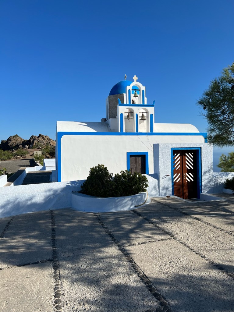 Church with blue roof on trail Fira to Oia Hike in Santorini, Greece
