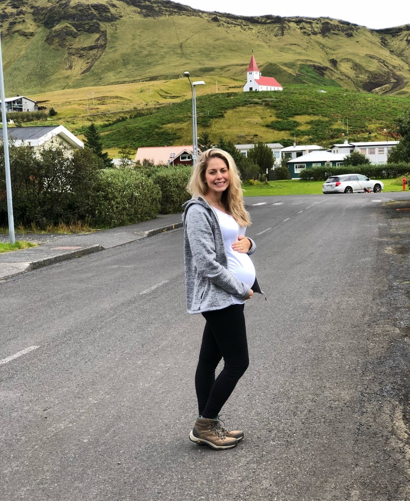 Pregnant woman standing in front of a church in Vik, Iceland