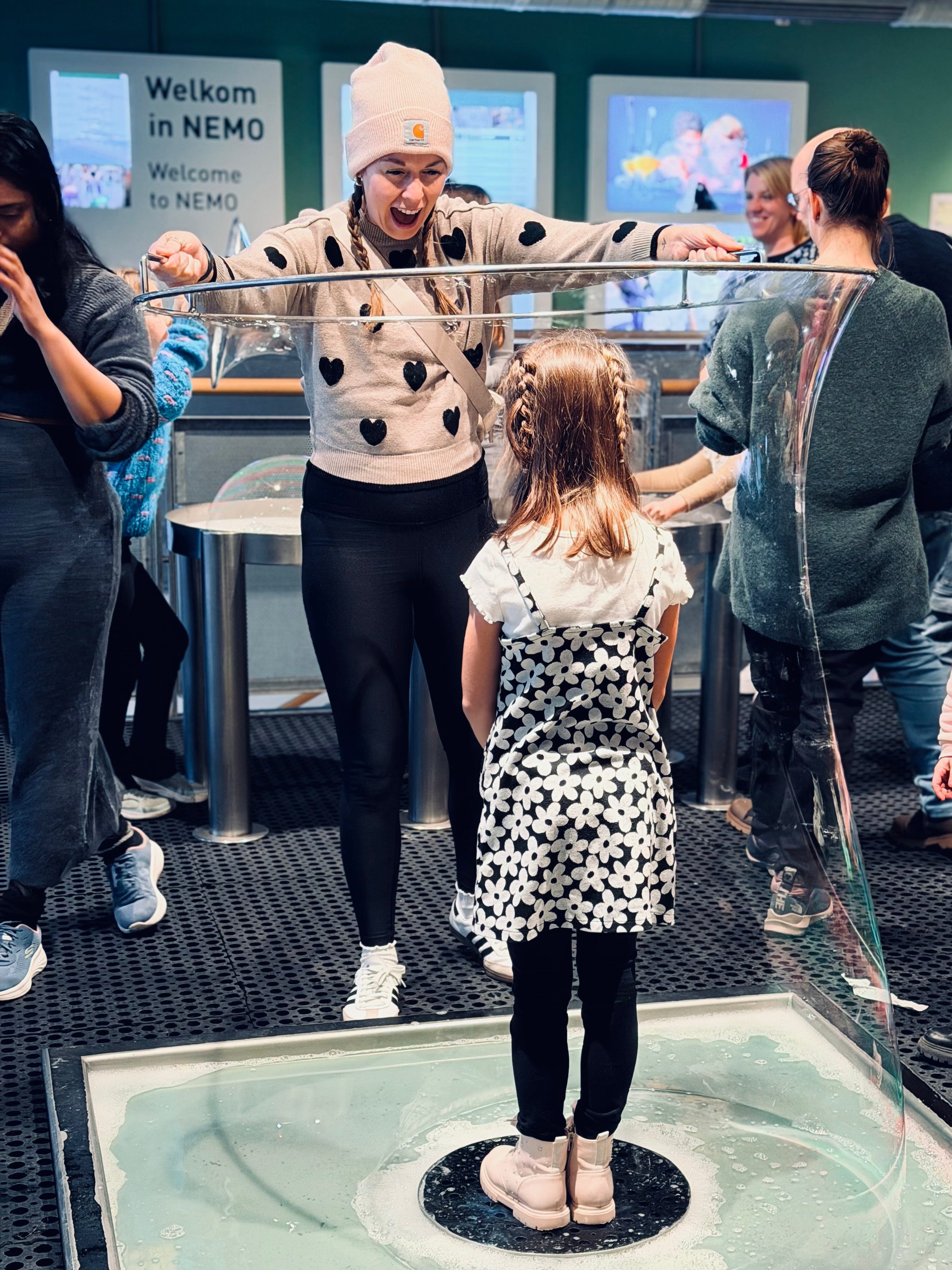 Mother pulling a bubble around her six year old's entire body at the NEMO Science Museum