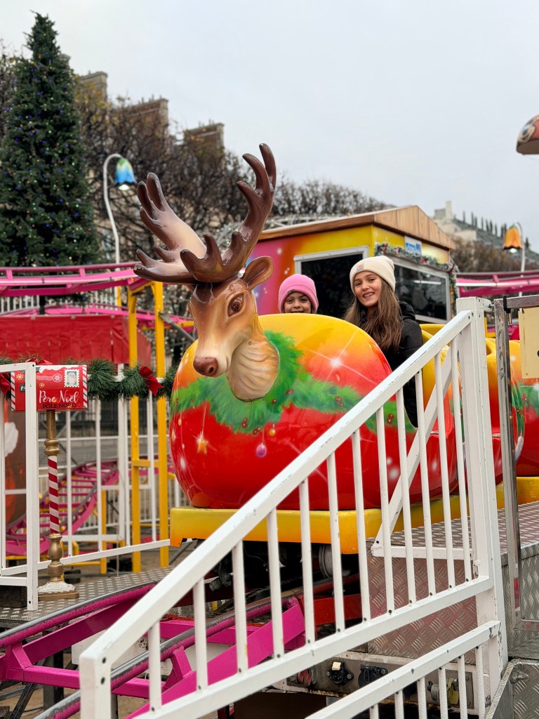 Girls riding Christmas roller coaster at market in Tuileries Garden