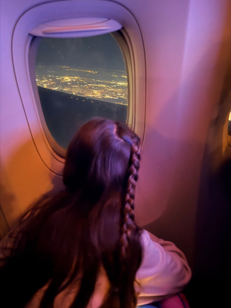 Daughter looking out airplane window when leaving Newark International Airport 
