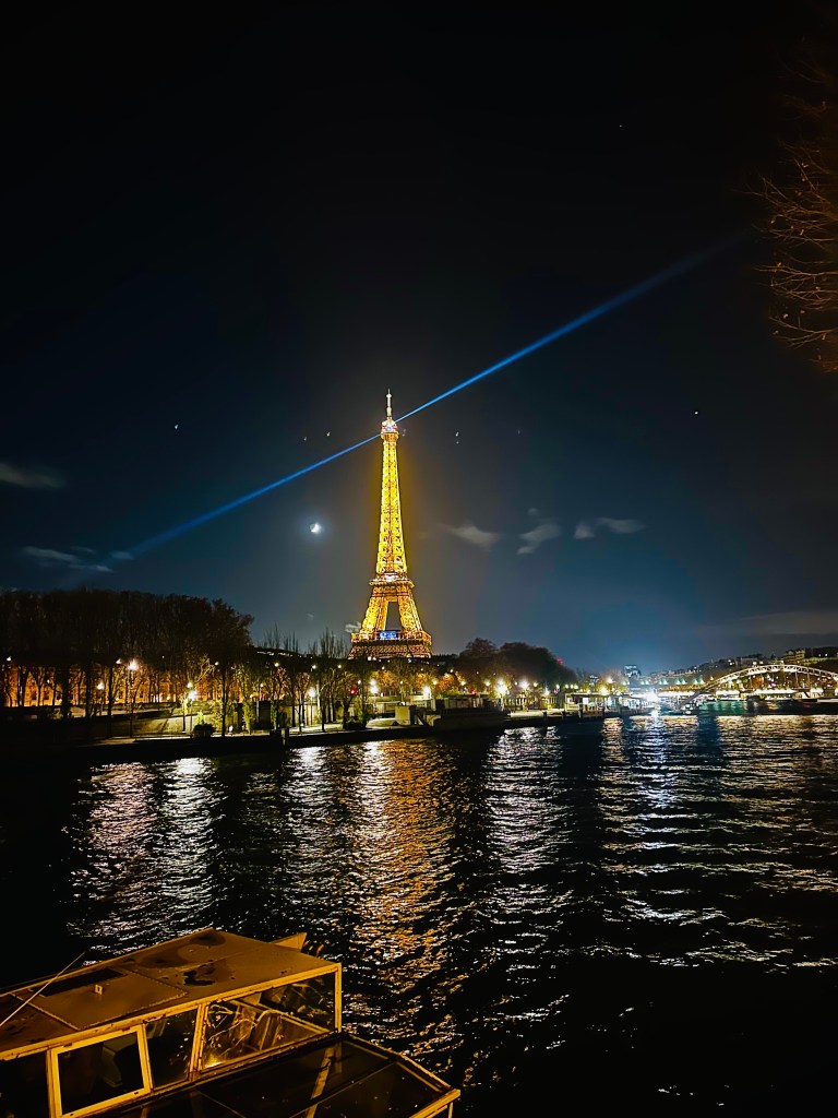 Eiffel Tower lit up at night over the Seine River