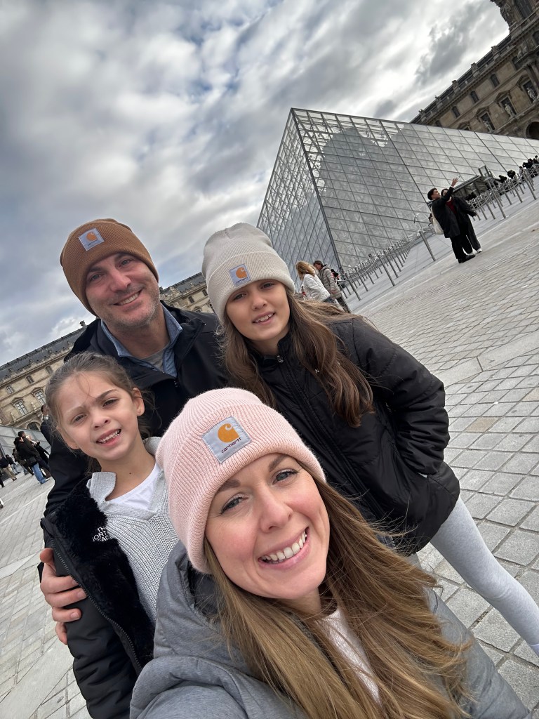 Family photo in front of the glass pyramid above the Louvre Museum 