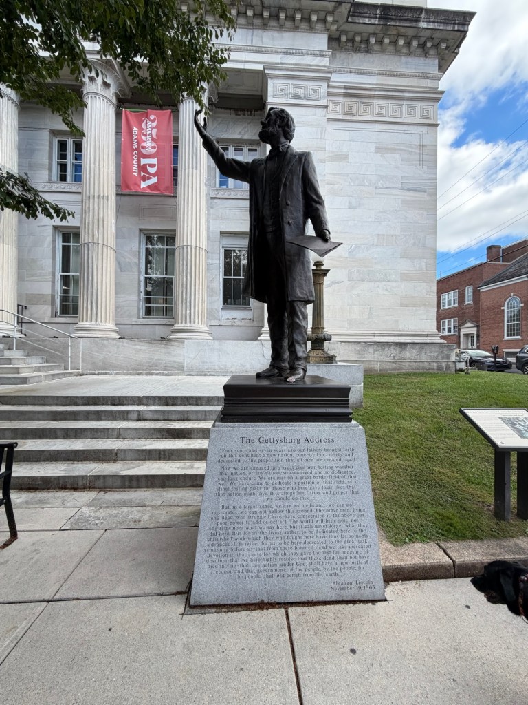 A statue of Abraham Lincoln in downtown Gettysburg with the Gettysburg Address inscribed below him 