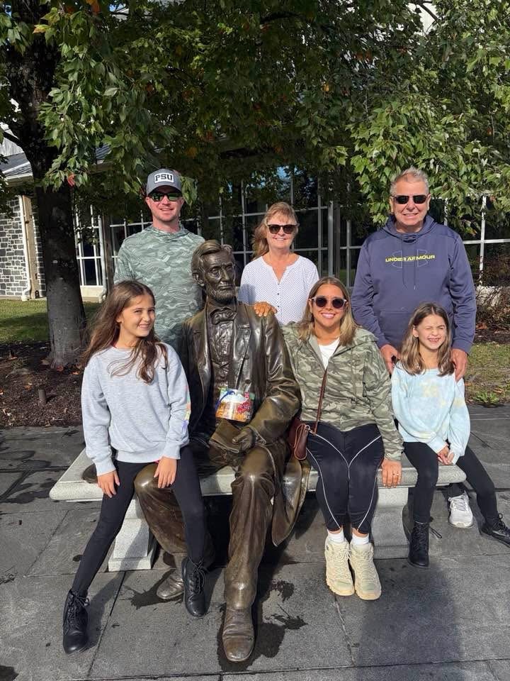 A family sitting on a bench with a statue of Abraham Lincoln at the Gettysburg National Military Park Museum and Visitor Canter